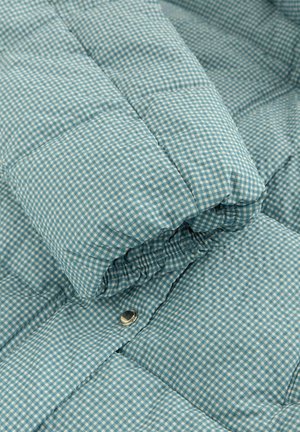 Quilted blue checkered fabric, featuring a pattern of small squares. Soft texture with a silver snap button detail.