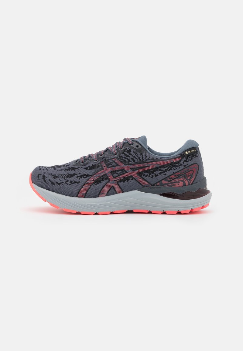 Chaussure de course gris foncé et rose avec empeigne à motifs, semelle épaisse gris clair, bande de roulement rose et étiquette Gore-Tex sur la section talon.