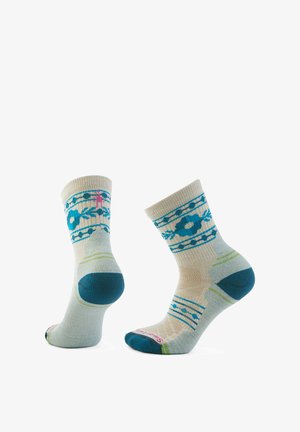 Mehrfarbige Crew-Socken aus einem weichen Stoff, mit einem floralen Muster in Blau und Grün auf einem hellbeigen Hintergrund.