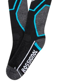 Calcetines negros y grises con patrones hexagonales, que presentan acentos turquesa y marca blanca. Están hechos de un tejido texturizado con áreas acanaladas.