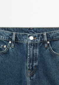 Blå denimjeans med hög midja, dragkedja och knäppning. Inkluderar vanlig sömnad, fem fickor och mässingsdetaljer.
