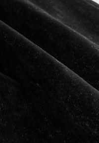 Fekete bársonyszövet, amely puha tapintású, finom árnyalateltérésekkel és sima, enyhén fénylő felülettel rendelkezik.