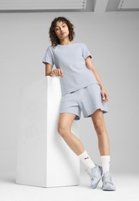 Lichtblauw sportoutfit met een T-shirt met korte mouwen en bijpassende shorts met een gestructureerde afwerking, aangevuld met grijze sneakers en witte sokken.