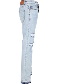 Jean en denim bleu clair avec une coupe slim. Présente des déchirures aux genoux, des bords effilochés et une taille cousue avec un patch en simili cuir.