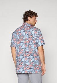 Short-sleeve shirt in light blue with coral and navy floral design. Features a camp collar and relaxed fit. Fabric appears lightweight.