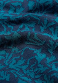 Mornarsko blago s teksturiranim vzorcem teal listja. Mehka, tkana tekstura z zapletenimi podrobnostmi, ustvarjenimi z kontrastnimi barvami.