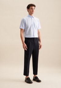 Una camicia azzurra chiaro a maniche corte con bottoni, abbinata a pantaloni a pieghe blu navy e scarpe in pelle nere. Design semplice con una vestibilità regolare.