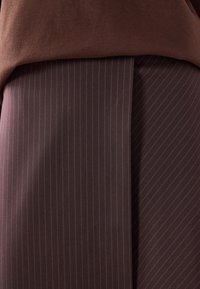 Tissu brun à couches, avec une section supérieure lisse et une section inférieure texturée à fines rayures foncées, créant un design visuellement contrasté.