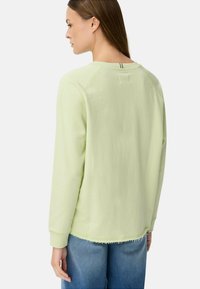 Lichtgroene lange mouwen sweater met een ronde halslijn en een rafelige onderrand. Heeft raglanmouwen en een subtiel achternaaddetail.