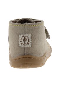 Botín de ante gris con suela de goma marrón. Presenta un acento de costura amarilla y una etiqueta de tela en la parte posterior.