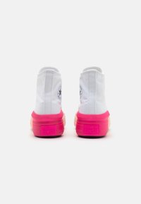 Pair of white high-top Converse sneakers with bright pink soles viewed from the back against a plain background.