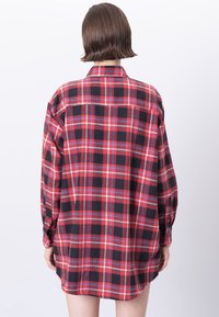 Rød og sort ternet flannel skjorte med knap-ned krave, lange ærmer og en løs pasform, med buet kant og rygdetalje.