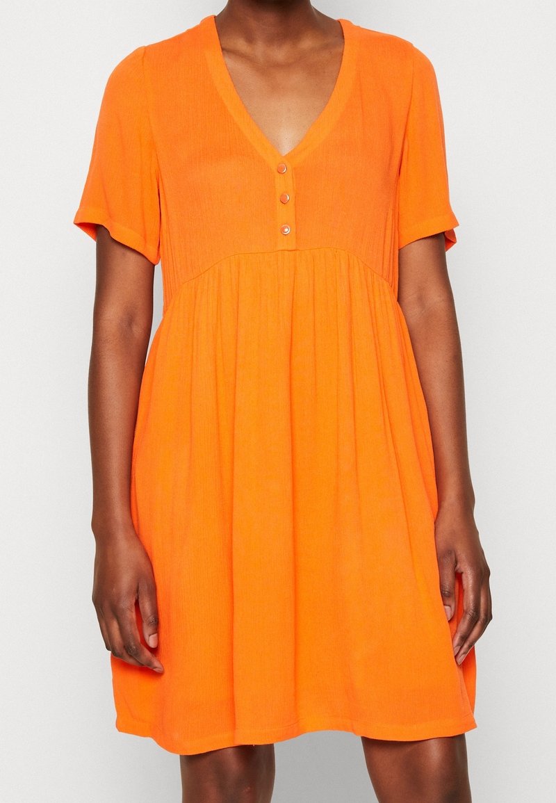 Robe à manches courtes et col en V de couleur orange vif. Dotée d'une patte de boutonnage sur le devant et d'une taille froncée, confectionnée dans un tissu léger et texturé.