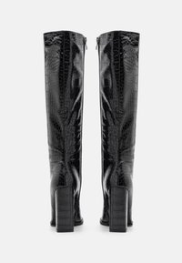 Bottes noires montant jusqu'au genou avec une texture crocodile, talons carrés et fermetures éclair à l'arrière. Matériau élégant et brillant avec une finition lisse.