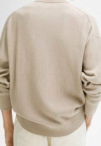 Beige, gerippter Strickpullover mit lässiger Passform. Verfügt über abgesenkte Schultern und aufgeschlagene Ärmel. Weicher Stoff und runder Ausschnitt.