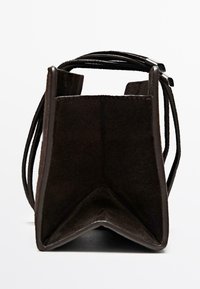 Borsa in suede marrone scuro con forma rettangolare strutturata, apertura superiore ben visibile e sottili doppie tracolle con punte in metallo, mostrata da un angolo inferiore.