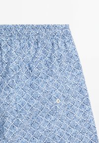 Pantaloni corti blu con un motivo geometrico in diverse sfumature di blu. Vita elastica con un piccolo dettaglio a bottone sulla parte frontale.
