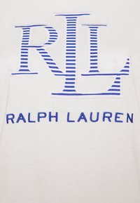 Vit bomulls t-shirt med en framträdande blå broderad "RL" logotyp och randig detalj ovanför texten "RALPH LAUREN."