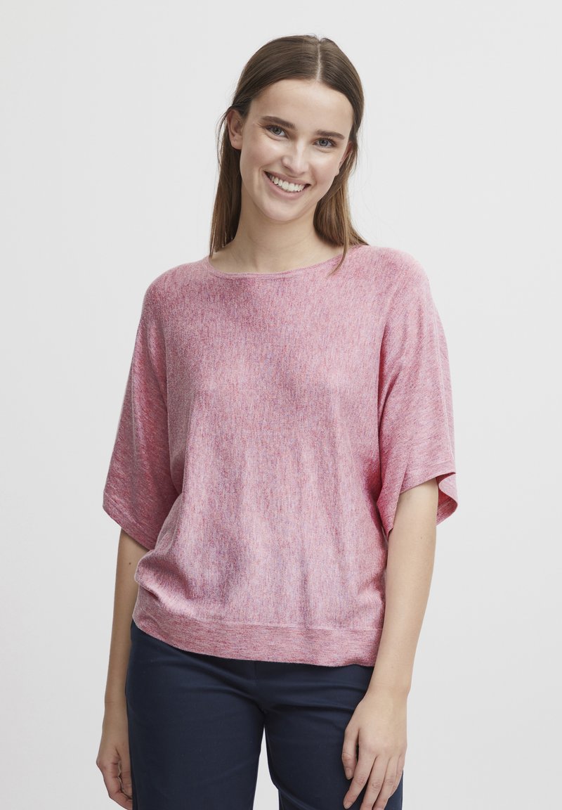 Roze, losse gebreide top met brede mouwen en een ronde halslijn. Getextureerde stof met een lichte heatherpatroon. Gecombineerd met donkere broeken.