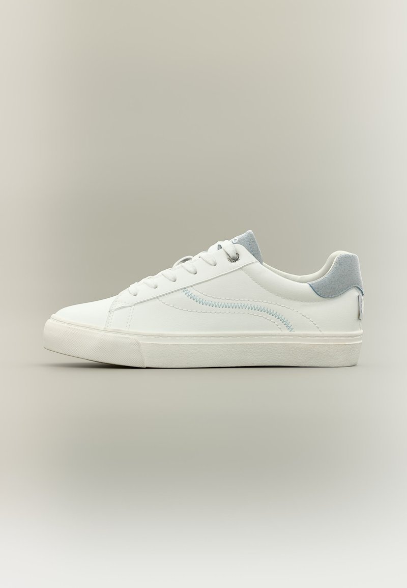 Άσπρο χαμηλό αθλητικό παπούτσι με ανοιχτογκρι τακούνι, άσπρα κορδόνια, διακριτική ζιγκ ζαγκ λεπτομέρεια στο πλάι και υφασμένη λαστιχένια σόλα σε μπεζ φόντο.