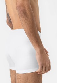 Boxer-briefs blancs en coton avec une texture douce. La taille présente un design sans couture, et le tissu semble léger et flexible.