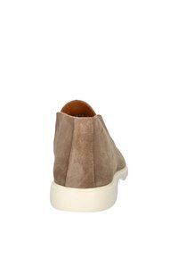 Bruine suède enkelschoen met een crèmekleurige rubberen zool, met een eenvoudig ontwerp en een gladde textuur. De achterkant heeft een ronde vorm.