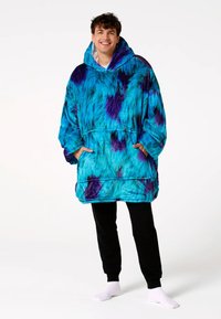 Mėlynos ir violetinės spalvos tie-dye stiliaus didelio dydžio antklodės tipo džemperis su dideliu gobtuvu, kišene, ilgomis rankovėmis ir minkšta, puria medžiaga.