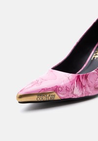 Ροζ μυτερή γόβα με μπαρόκ σχέδιο και μεταλλική χρυσή μύτη με χάραξη "Versace Jeans Couture".