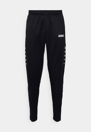 Pantalons de sport noirs avec jambes fuselées, ceinture élastique, logo "JAKO" en blanc et accents décoratifs de points gris le long des côtés.