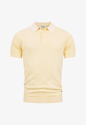 Polo en maille jaune clair à manches courtes avec ourlet et poignets côtelés, patte à deux boutons et col blanc.