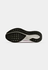 Semelle de chaussure avec motif d'adhérence en caoutchouc noir sur base blanche et petit logo embossé près du talon.