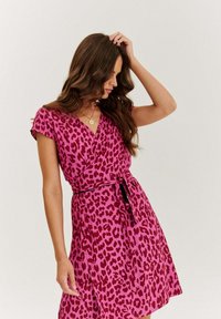 Ružové zavinovacie šaty so vzorom leopardie srsti v tmavo červenej farbe, krátke rukávy a zviazaný pás. Hladká látka s voľnou sukňou.