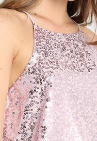Haut à sequins avec un col licou, présentant un dégradé de tons roses et argentés et une surface texturée créée par des sequins superposés.