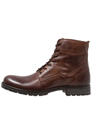 Bottine en cuir marron avec une finition lisse, bout rond et design à lacets. Présente des accents de couture et une semelle en caoutchouc texturée.