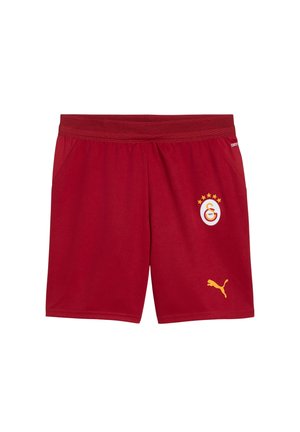 Rode sportshorts met elastische tailleband, met een geel Puma-logo en een voetbalclubwapen met sterren op het rechterbeen.