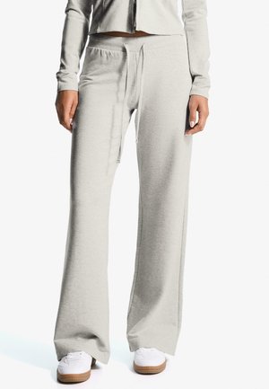 Light gray sweatpants made of soft fabric, featuring a relaxed fit, adjustable drawstring waist, and side pockets. Paired with white sneakers.