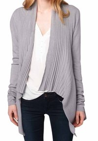Ljusgrå ribbad cardigan med öppen front, långa ärmar och en nederkant som lutar framåt, bärs över en vit topp och mörka jeans.