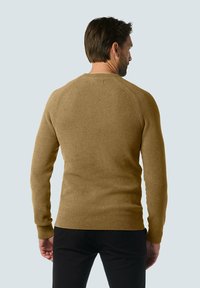 Bruine gebreide trui met een gestructureerd oppervlak, met lange mouwen en een ronde halslijn, van achteren weergegeven tegen een lichte achtergrond.