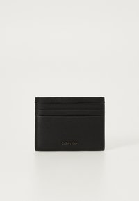 Svart lær kortholder med teksturert finish, flere kortholdere og et debossed Calvin Klein-logo foran.