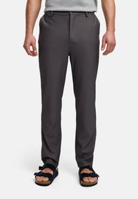 Pantalones a rayas grises con un corte ajustado, que presentan una textura suave y una cinturilla. Combinados con sandalias negras de tipo deslizante.