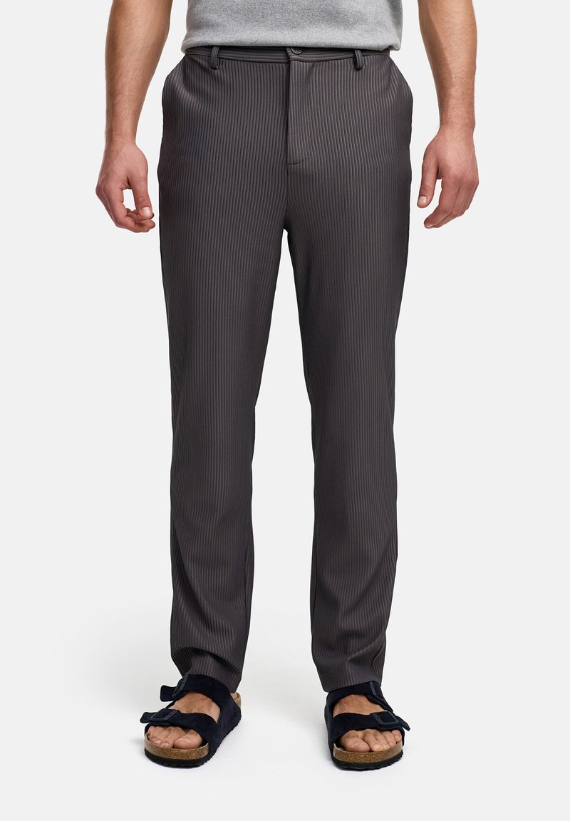 Pantalones a rayas grises con un corte ajustado, que presentan una textura suave y una cinturilla. Combinados con sandalias negras de tipo deslizante.