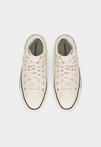 Ζευγάρι πορσελάνινων Converse αθλητικών παπουτσιών με λευκά κορδόνια και μικρά στολίδια σε σχήμα λουλουδιού στα πλαϊνά, σε επισκόπηση από πάνω.