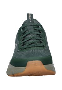 Green athletic shoe with mesh upper, ridged design, lace-up closure, and a gum rubber outsole. Features a logo on the side and textured accents.