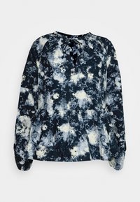 Blusa de mangas longas em azul marinho escuro, com um padrão abstrato branco, gola redonda com um detalhe em laço e uma bainha peplum franzida.