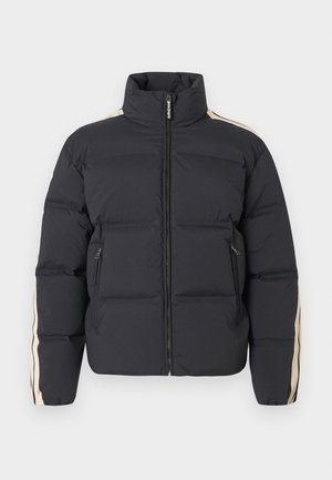 Doudoune bleu marine foncé avec un col montant, fermeture éclair, et des rayures latérales beiges. Dispose de deux poches avant zippées et d'une texture matelassée.