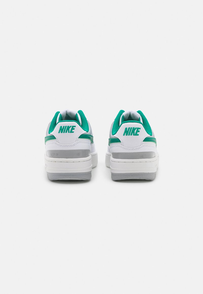 Baskets Nike blanches et turquoise avec une tige en cuir lisse, un col rembourré et une semelle légèrement épaisse avec un détail texturé au niveau du talon.