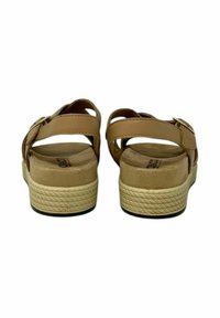 Sandali in pelle marrone con cinturini regolabili, suole imbottite e suole in gomma testurizzata per aderenza. Stile piatto e a piattaforma.