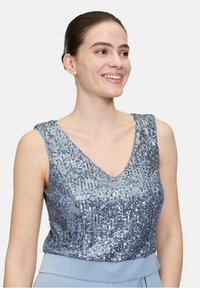 Haut sans manches en bleu clair avec un décolleté en V, couvert de sequins argentés. Présente un design ajusté et une texture lisse.