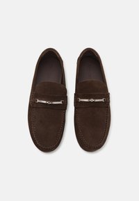 Brown suede loafers featuring a polished silver accent and stitching details. Smooth texture with a classic slip-on design.