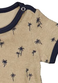 Béžová košile s krátkým rukávem a námořnickým lemem, která má texturovanou tkaninu a jsou na ní rozptýlené vzory palmových stromů. Patentka na límci.